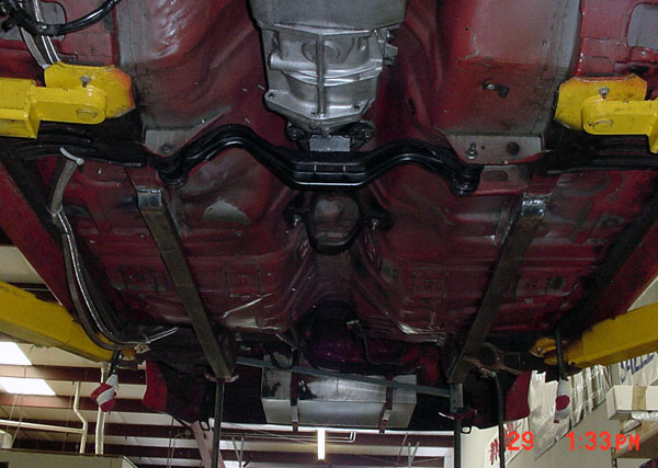 Underside of a car on a lift, showing the transmission and exhaust system