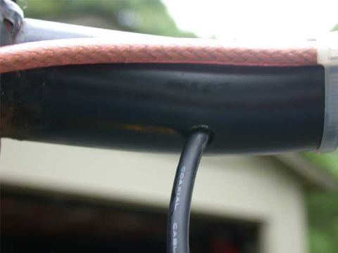 1996 Ford Bronco - Extreme close-up of a CB antenna mount with red braided sleeving over the shaft and a black coaxial cable, labeled "COAXIAL CABLE", exiting…