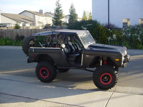 1991 Ford Bronco - This modified Ford Bronco, likely from the late 1970s, is shown from a three-quarter front angle on a residential street.
