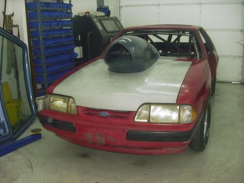 1990 Ford Mustang - This 1990 Ford Mustang features a prominent hood scoop and visible roll cage, indicating a focus on performance modifications.