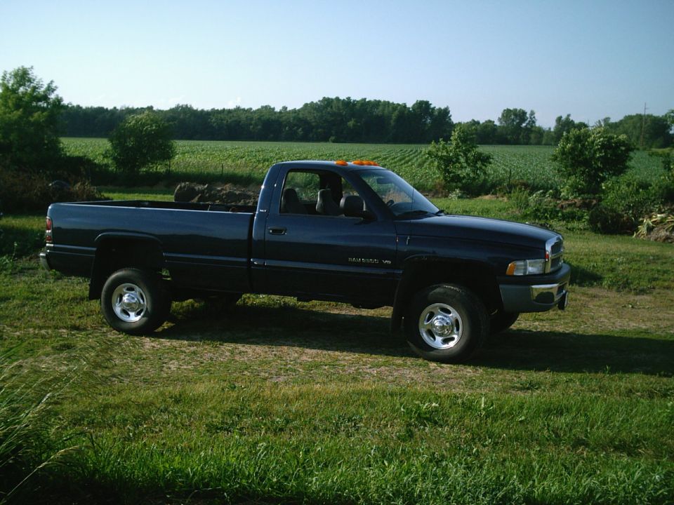 Dark blue 2001 Dodge 2500 pickup truck parked on grass with a field in the background