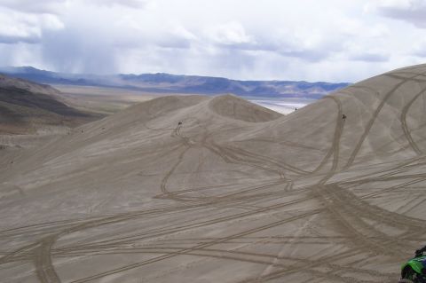 1994 Ford F-150 - A vast expanse of sand dunes with tire tracks, under a dramatic cloudy sky.