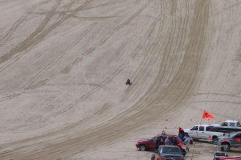 1994 Ford F-150 - People are enjoying recreational activities on a sandy terrain with vehicles parked nearby.