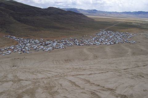 1994 Ford F-150 - A vast desert scene shows a large congregation of recreational vehicles and trailers spread across the sandy terrain.