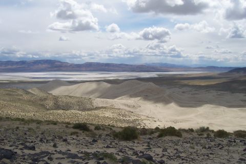 1994 Ford F-150 - A vast desert landscape unfolds with rolling sand dunes and distant mountains under a dramatic sky, a prominent "SUPERMOTORS" logo.