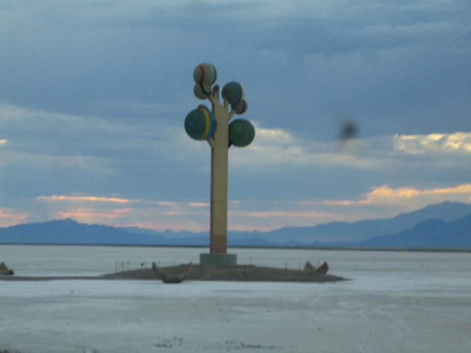 tall column sculpture topped with colorful spheres on a salt flat at dusk