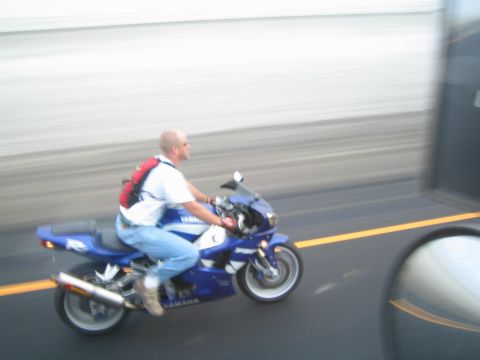 1990 Ford Bronco - man rides a blue Yamaha sportbike along a road, the background streaked with motion blur.