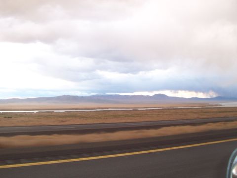 1994 Ford F-150 - A wide view of a desert highway with mountains in the distance under a dramatic sky.