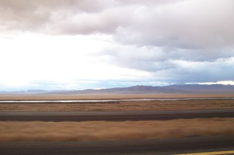 1994 Ford F-150 - A vast, open landscape stretches towards distant mountains under a dramatic, cloudy sky, with a body of water in the mid-ground.