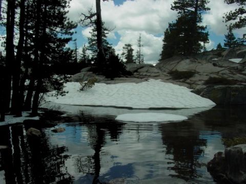 1986 Ford Bronco - A mountain lake scene with snow remnants on the shore and a small ice floe in the water.