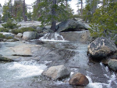 1986 Ford Bronco - A natural scene of a stream flowing through a rocky landscape with trees in the background.