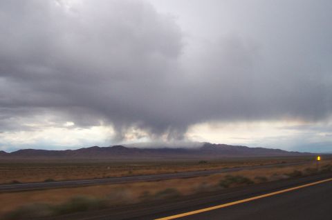 1994 Ford F-150 - A dramatic sky with dark storm clouds looms over a vast, arid landscape and a highway.