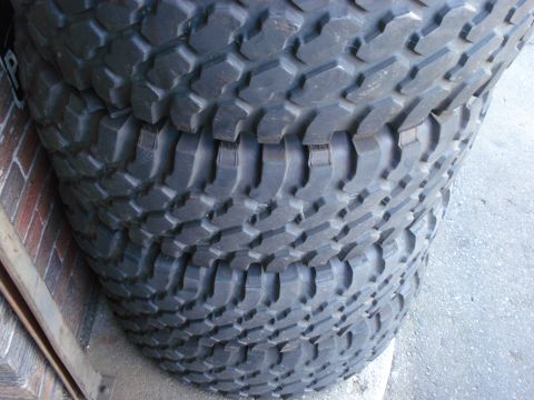 1994 Ford Bronco - Several large, knobby tires are stacked together, leaning against a brick wall.