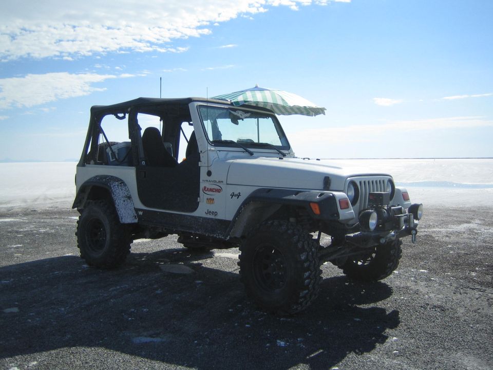 white lifted Jeep Wrangler with doors off parked on a salt flat