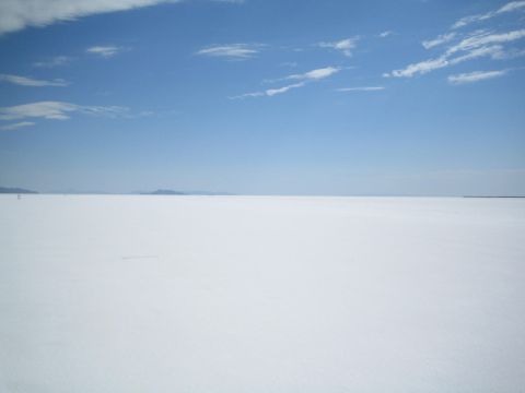 1990 Ford Bronco - bright white salt flat stretches to the horizon where low hills meet a clear blue sky.