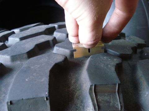 1994 Ford Bronco - A razor blade is used to check the tread depth of a off-road tire.