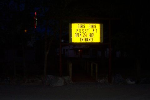 1994 Ford F-150 - A brightly lit sign at night advertises services and hours of operation, with the word 'ENTRANCE' visible.