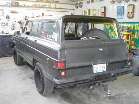1977 Jeep Wagoneer - This Jeep Grand Wagoneer is parked indoors, showing its rear exterior and spare tire.