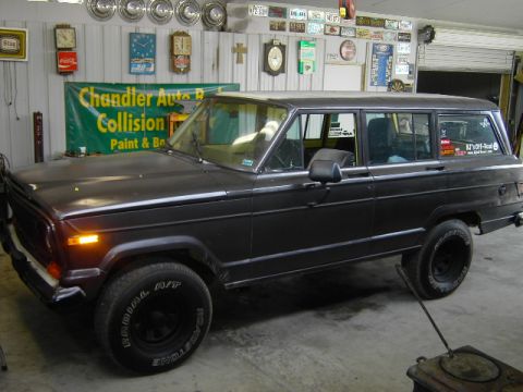 1977 Jeep Wagoneer - This Jeep Grand Wagoneer is parked indoors, with a "Chandler Auto Repair" banner visible in the background.