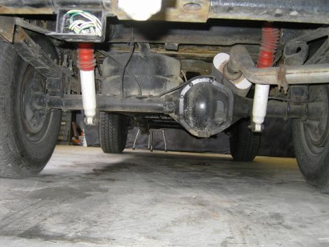 1977 Jeep Wagoneer - The rear suspension and drivetrain components of a vehicle are visible from underneath.