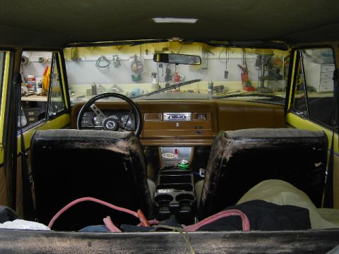 1977 Jeep Wagoneer - Interior view of a 1977 Jeep Wagoneer, worn seats and a cluttered dashboard.