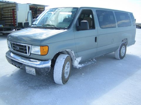 1990 Ford Bronco - gray Ford Econoline passenger van with salt-caked tires and a visible license plate sits on a white flat.