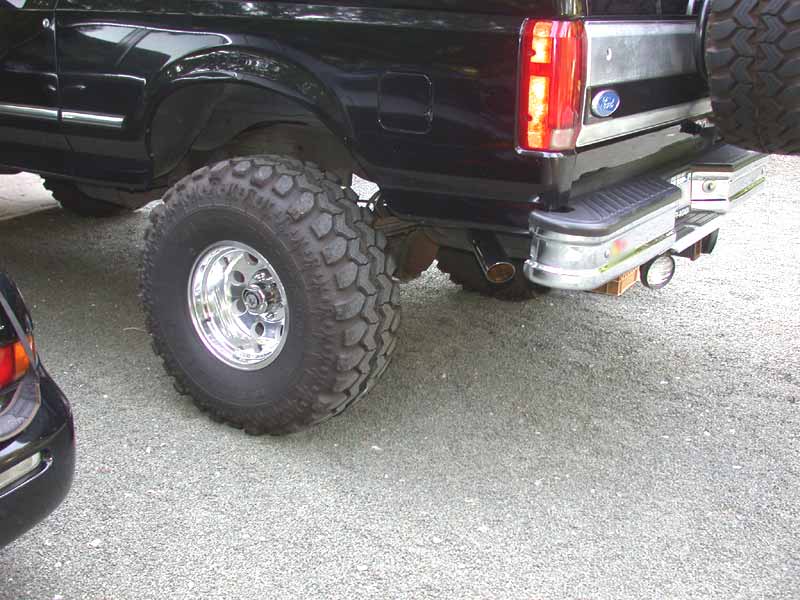 Rear quarter of lifted black Ford Bronco with mud tire, polished wheel and chrome bumper