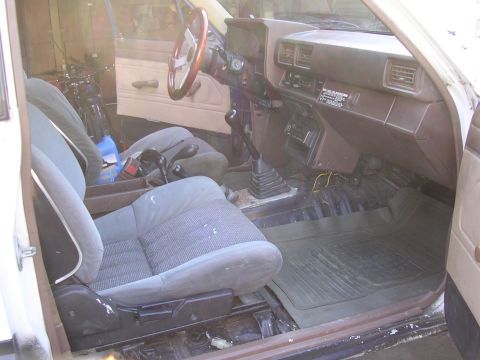 1985 Toyota 4Runner - The interior of the vehicle shows worn seats and a dashboard with various controls and vents.