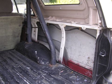 1985 Toyota 4Runner - The rear interior of a vehicle shows a roll bar and the cargo bed with visible wear and tear.