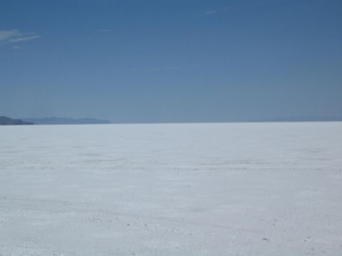 1990 Ford Bronco - broad white salt flat extends to a line of distant mountains beneath a clear blue sky.