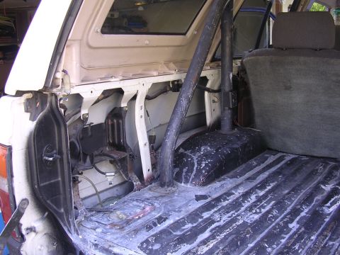 1985 Toyota 4Runner - The interior cargo area of a vehicle shows a roll bar and distressed flooring, with visible interior components.