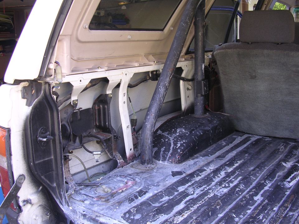 Stripped Toyota 4Runner rear cargo area showing roll bar leg and bare bed floor