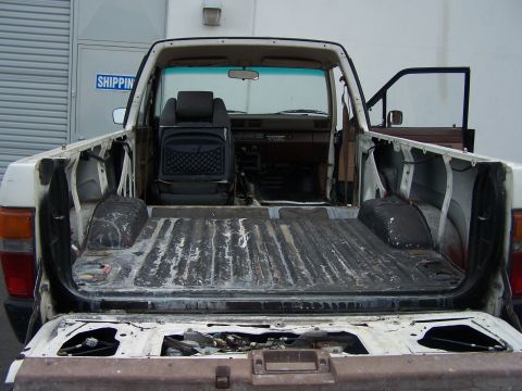 1985 Toyota 4Runner - The interior of a pickup truck is disassembled, revealing the empty bed and exposed components.