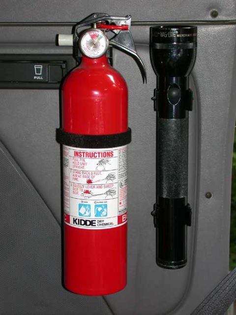 1996 Ford Bronco - Close-up of a red Kidde dry chemical fire extinguisher with pressure gauge and instruction label, strapped in a black quick-release bracket…