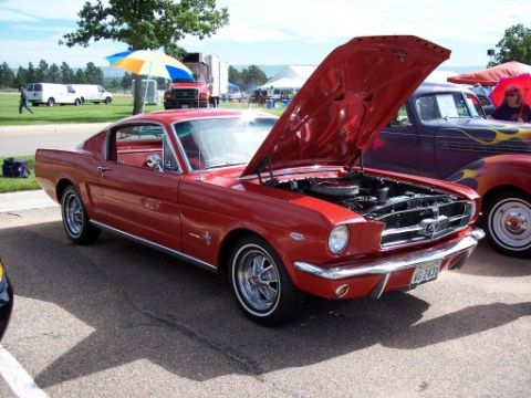 1972 Ford Ranchero - A red 1965 Ford Mustang is displayed with its hood open, parked next to another custom vehicle.