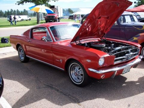 1972 Ford Ranchero - A red 1965 Ford Mustang coupe is parked with its hood open, revealing the engine bay.