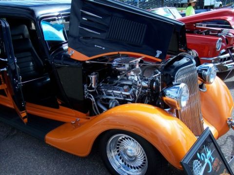 1972 Ford Ranchero - A black and orange custom hot rod is displayed with its hood open, revealing a chrome engine and custom wheels.