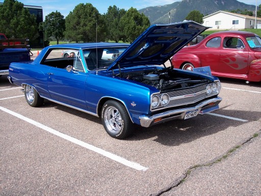 Blue 1965 Chevrolet Chevelle hardtop with hood open at an outdoor car show