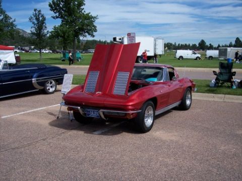 1972 Ford Ranchero - A red 1963 Chevrolet Corvette coupe is displayed with its hood open next to a dark blue convertible.