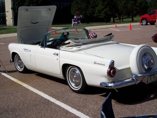 White Ford Thunderbird roadster with hood up and Continental kit at a car show