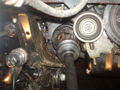 1995 Ford Probe - This image shows a close-up view of greasy engine and suspension parts, including a CV joint and a belt tensioner pulley.