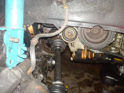 1995 Ford Probe - Detail of a car's undercarriage showing the axle, engine belt, and suspension components with grease accumulation.