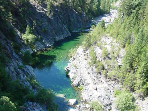 1986 Ford Bronco - A scenic view of a river flowing through a rocky canyon surrounded by evergreen trees.