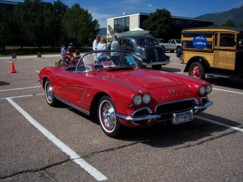 1972 Ford Ranchero - Red 1959 Chevrolet Corvette convertible parked in a lot with other vehicles visible.