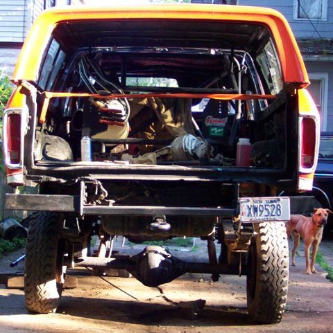 1978 Ford Bronco - The rear of a 1978 Ford Bronco, modified with a roll cage and an orange exterior, is shown with its tailgate open.