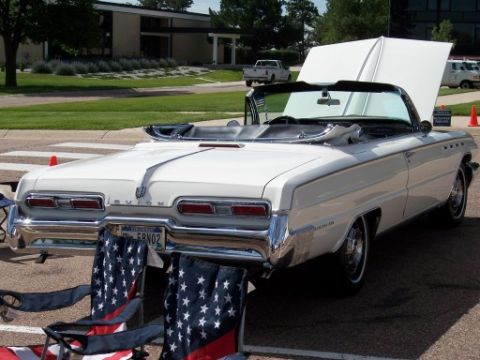 1972 Ford Ranchero - A white 1962 Buick convertible is shown from the rear with its hood open, parked outdoors with American flag chairs nearby.