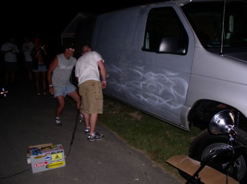 1978 Ford Mustang II - A van with flame graphics is parked on asphalt at night, with people standing nearby.