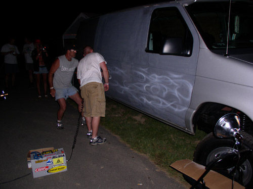 Silver van with white flame graphics, side view, parked on asphalt at night