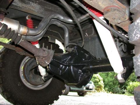 1996 Ford Bronco - Underbody shot of a rear leaf-spring axle with a glossy black-painted differential housing, white-bodied shock absorber and a red coil-over…