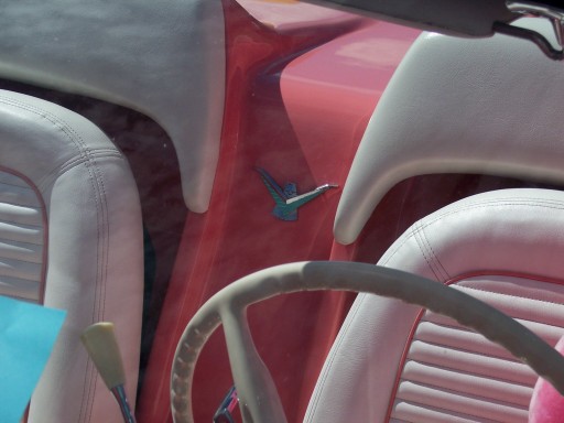 Classic car interior with cream bucket seats, red dash and white steering wheel